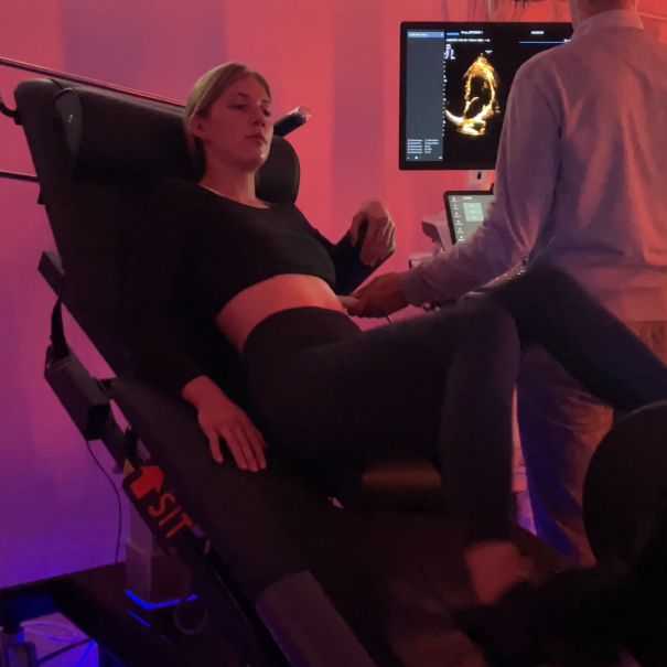 Vue 3/4 du divan d'effort ULKE avec ergomètre intégré et d'un cardiologue pesant une échographie – Koch Evolution
