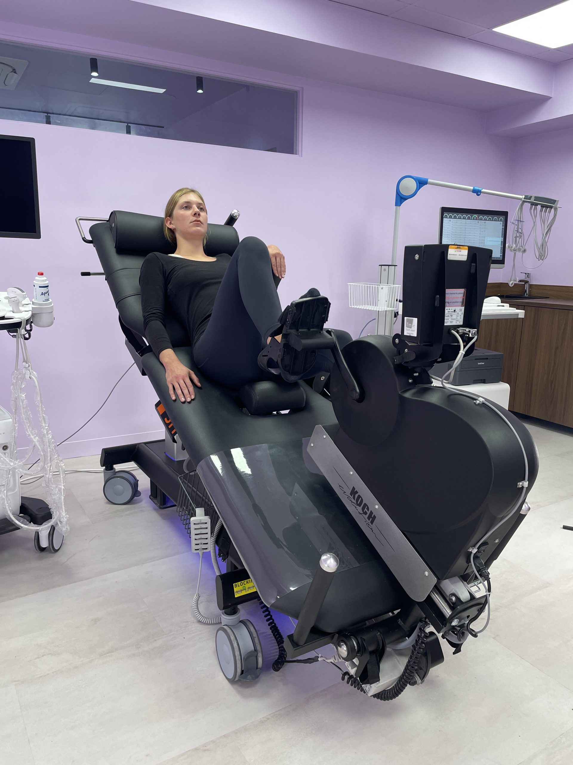 divan ergométrique d'échocardiographie en position d'effort latérale avec un patient se maintenant au calage d'aisselle et utilisant l'ergomètre.